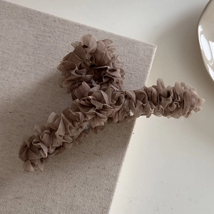 Vue détaillée du tulle marron plissé sur une grande pince à cheveux élégante