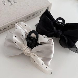 Close-up of elegant bow hair clips in black and white polka dot mesh on white background