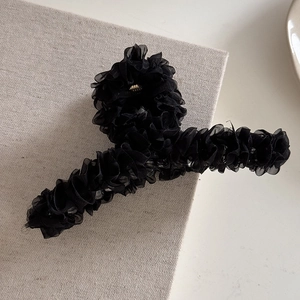Gros plan sur la texture en mousseline noire plissée d'une grande pince à cheveux