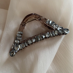 Close-up of a smoke-brown triangular hair claw clip with sparkling grey rhinestones