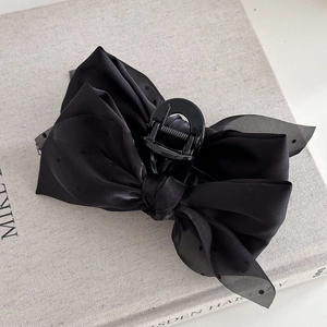 Close-up of a vintage black bow hair claw clip with polka dot mesh on a book background