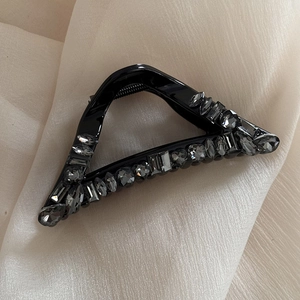 Close-up of a luxury black triangle hair claw clip with sparkling dark grey rhinestones