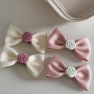 Dettaglio di fermagli per capelli a fiocco con camelia in tessuto crema e raso rosa
