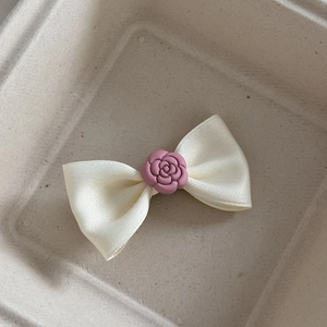 Dettaglio di un fermaglio per capelli a fiocco crema con camelia rosa centrale