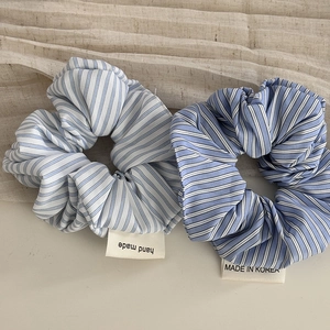 Blue striped fabric scrunchies with lace trim and handmade labels on linen background
