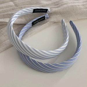 Blue and white striped fabric headbands with handmade label in a minimalist style