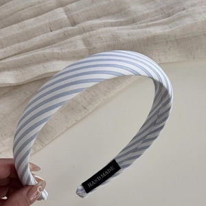 Detail of blue and white striped fabric headband with black HAND MADE woven label