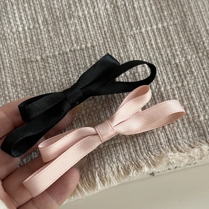 Gros plan de barrettes à nœud en ruban noir et rose montrant la texture du tissu côtelé