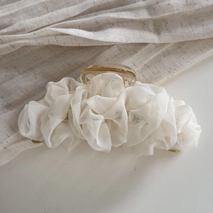 Detail van grote haarklem met wit geplooid organza op een barnsteenkleurige harsbasis