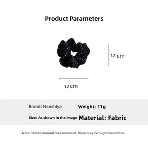 Détail d'un chouchou en tissu noir à pois avec des dimensions de 12 cm de diamètre