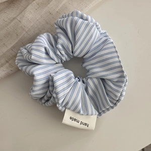 Detail of blue and white striped fabric scrunchie with a hand made woven label
