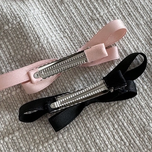 Vue détaillée des pinces crocodiles en métal au dos des barrettes à nœuds en satin rose et noir