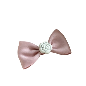 Fermaglio con fiocco in raso rosa e fiore di camelia bianca su sfondo bianco pulito