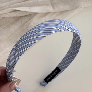 Detail of blue striped fabric hair scrunchie with Hand Made label and lace texture