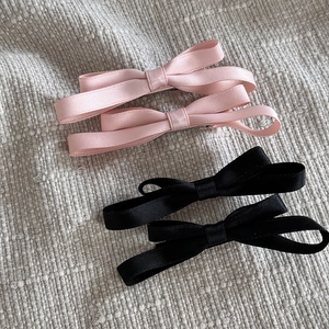 Détail de pinces à cheveux nœuds en ruban de satin rose et noir sur fond de tissu texturé
