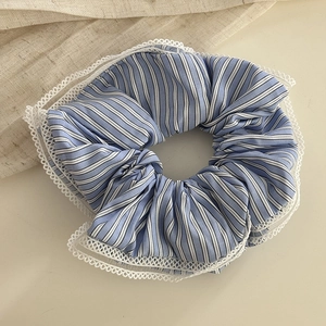 Detail of blue and white striped fabric scrunchie with delicate white lace edging