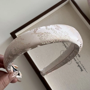 Close-up of champagne gold floral embroidery on thick vintage style padded headband