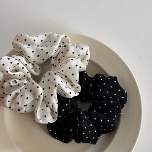 Gros plan de chouchous en mousseline à pois noirs et blancs sur une assiette en céramique
