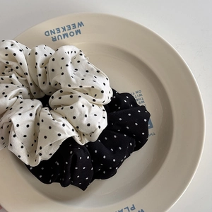 Détail des chouchous élastiques à motifs à pois sur une assiette en céramique blanche