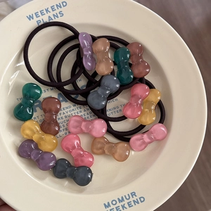 Close-up of colorful jelly bow hair ties with elastic bands in a decorative ceramic plate