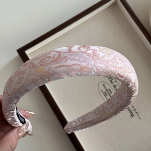 Close-up of pink jacquard fabric headband with vintage golden floral embroidery pattern