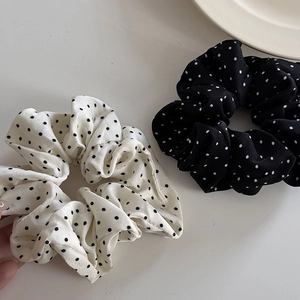 Gros plan sur un lot de chouchous en mousseline à pois noir et blanc sur fond clair