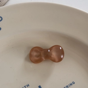 Detail of amber translucent bow hair tie on a decorative cream ceramic plate