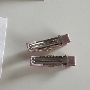 Vue détaillée du dos des barrettes en satin rose montrant la pince crocodile en métal