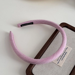 Detail of pink fabric headband with handmade label on minimalist wooden display tray
