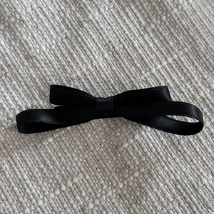 Détail du nœud en ruban de satin noir à double couche avec une texture lisse et brillante