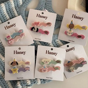 Detail view of handmade macaron hair clips with cute cartoon animals on a display card