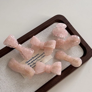 Lot de barrettes en acétate rose marbré avec motifs cœur et nœud sur un plateau