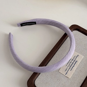 Detail view of purple fabric headband showing fine twill texture and Handmade inner label