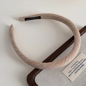 Detail of handmade padded headband featuring beige twill fabric texture and black woven label