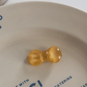 Close-up of translucent yellow resin bow hair clip with jelly-like texture and cat-eye luster