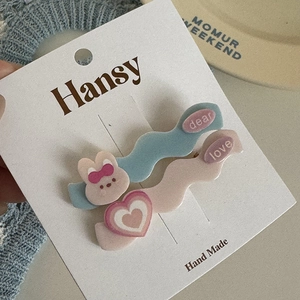 Detail view of wavy hair clips featuring cute cartoon rabbit and heart designs on display card