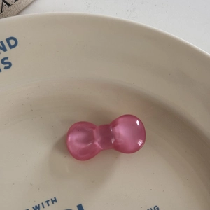 Macro shot of a cute translucent pink resin bow hair accessory on a beige dish