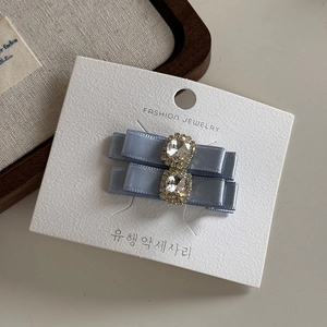 Détail de barrettes nœuds en satin bleu clair avec strass sur carte de support