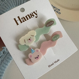Detail view of cute cartoon dog and bear hair clips on a decorative display card