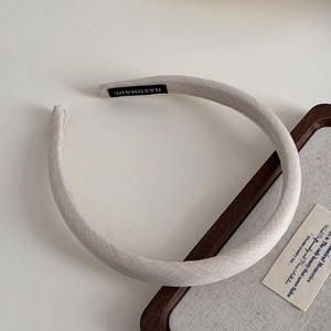 Close-up of handmade beige fabric headband showing fine woven texture and inner label