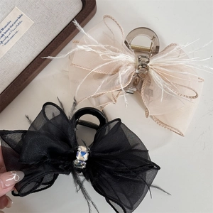 Elegant bow hair claws with feathers, mesh, and crystals in black and beige tones