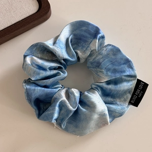 Close-up of blue marble silk scrunchie with Blind for Love woven label detail