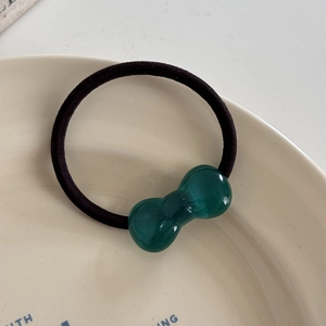 Detail of high-elasticity black hair tie with a translucent green acrylic bow ornament