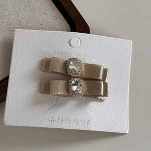 Détail de la barrette nœud en satin champagne avec un grand cristal et des strass brillants