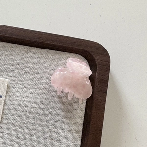 Vue rapprochée d'une mini pince à cheveux en acétate rose translucide avec texture marbrée
