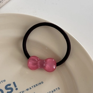 Macro view of pink resin bow hair tie with translucent finish on ceramic plate