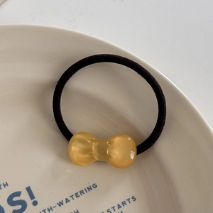 Detailed close-up of a high-elastic black hair tie with a translucent amber resin bow