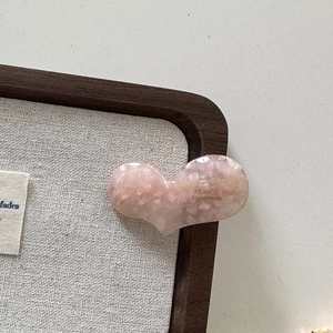 Gros plan d'une pince à cheveux en acétate rose marbré avec texte France Handmade doré
