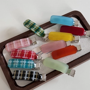 Set of 10 colorful acetate checkered and solid color duckbill hair clips on a wood tray