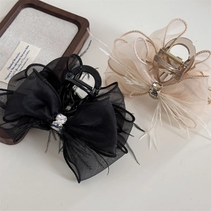 Close-up of elegant hair claw clips with mesh bow, delicate feathers and crystal accents